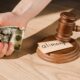 cropped view of man holding crumpled dollar banknote near gavel and paper with alimony lettering on