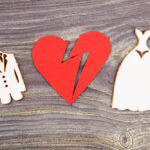 Divorce and canceling marriage concept. Broken heart and wedding dresses on wood.