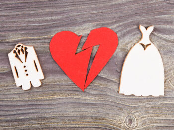 Divorce and canceling marriage concept. Broken heart and wedding dresses on wood.